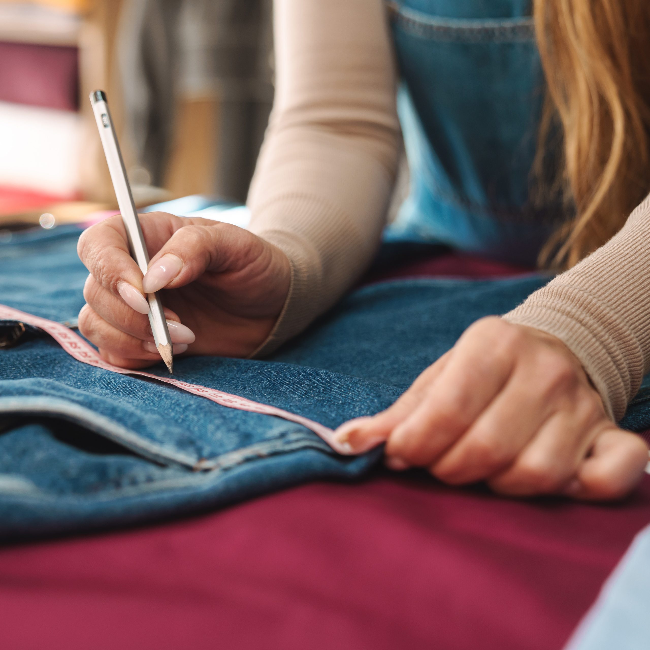 Cropped photo of mature woman seamstress measuring jeans while working in atelier