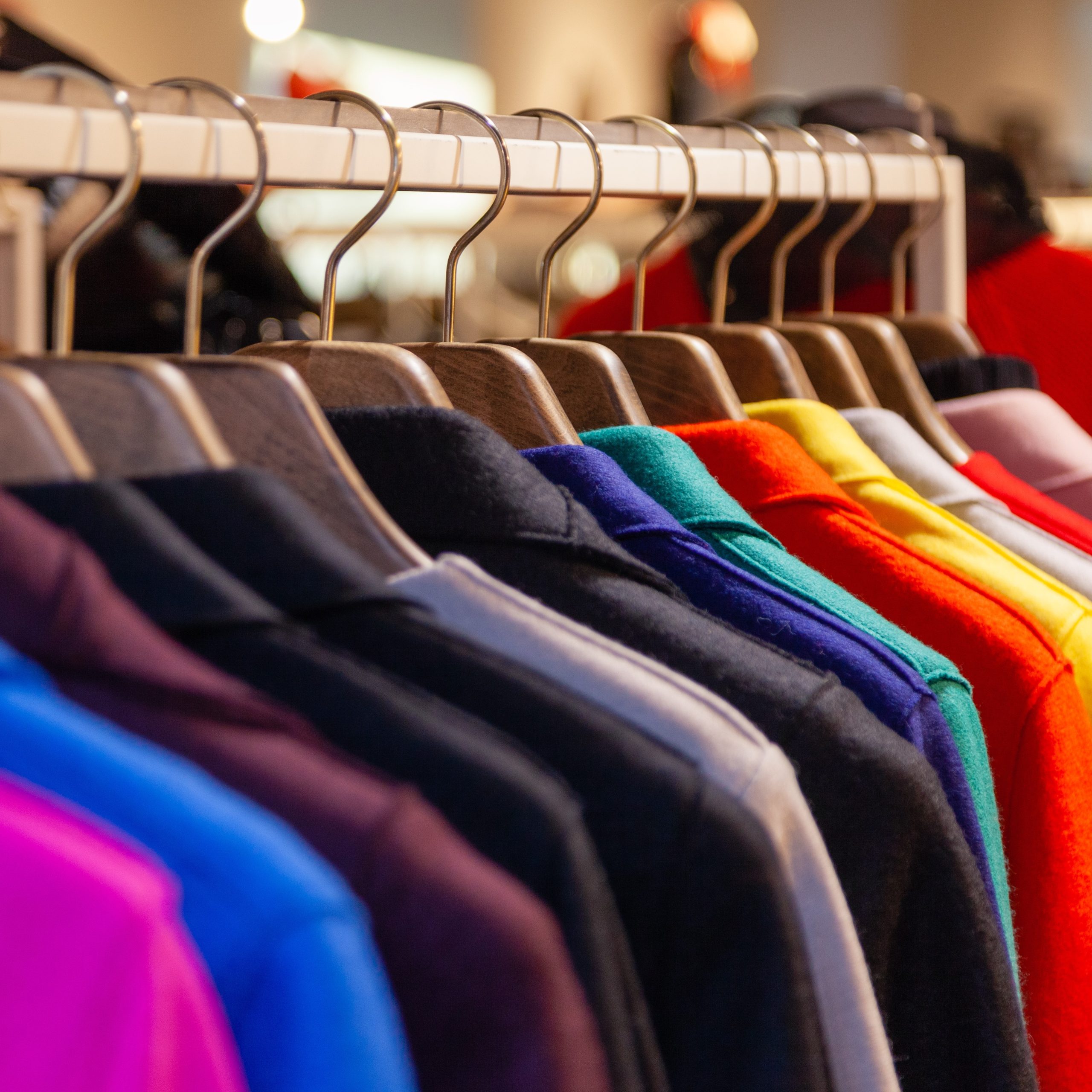 Closeup colorful male, female clothes in boutique hanging on hangers, clothing rack on metal stand. Concept opening luxury shop, shopping mall, store sale, retail fashion store, second hand outlet