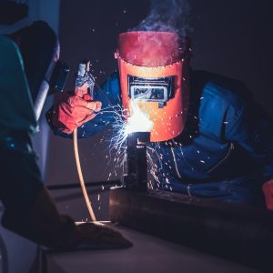 Metal welding steel works using electric arc welding machine to weld steel at factory. Metalwork manufacturing and construction maintenance service by manual skill labor concept.